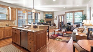 A spacious kitchen with wooden cabinets, a central island, and pendant lighting.
