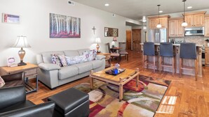A spacious living room with a sofa, coffee table, and a dining area with chairs.
