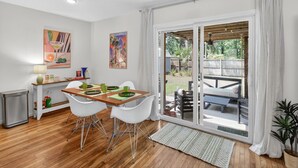 A dining area with a wooden table, white chairs, and a view of the backyard through a sliding glass door. - 5BR Group House | Fire Pit, Movie Deck & Fun Games (Charleston)