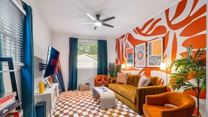 A living room with a checkered floor, a sofa, a coffee table, and a ceiling fan. - 5BR Group House | Fire Pit, Movie Deck & Fun Games (Charleston)