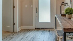 A hallway with a frosted glass door, a wooden bench, a potted plant, and a modern chandelier. - Rooftop retreat with views of Belmont-Near The Gulch! (Nashville)