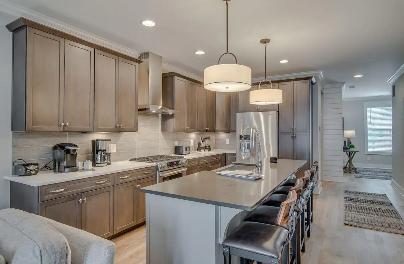 A modern kitchen with stainless steel appliances, wooden cabinets, and a central island with bar stools.