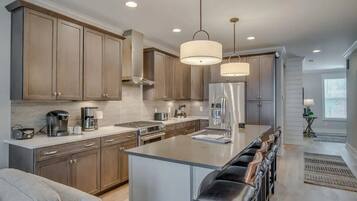 A modern kitchen with stainless steel appliances, wooden cabinets, and a central island with bar stools.