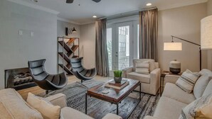 A modern living room with a ceiling fan, a fireplace, a sofa set, a coffee table, and a lamp. - Rooftop retreat with views of Belmont-Near The Gulch! (Nashville)