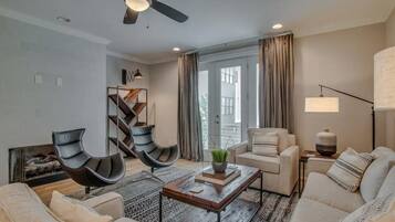 A modern living room with a ceiling fan, a fireplace, a sofa set, a coffee table, and a lamp.