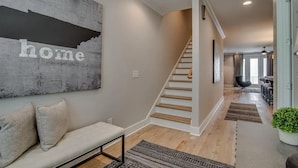 A modern interior with a staircase, a sofa with cushions, and a wall with the word "home" on it. - Rooftop retreat with views of Belmont-Near The Gulch! (Nashville)