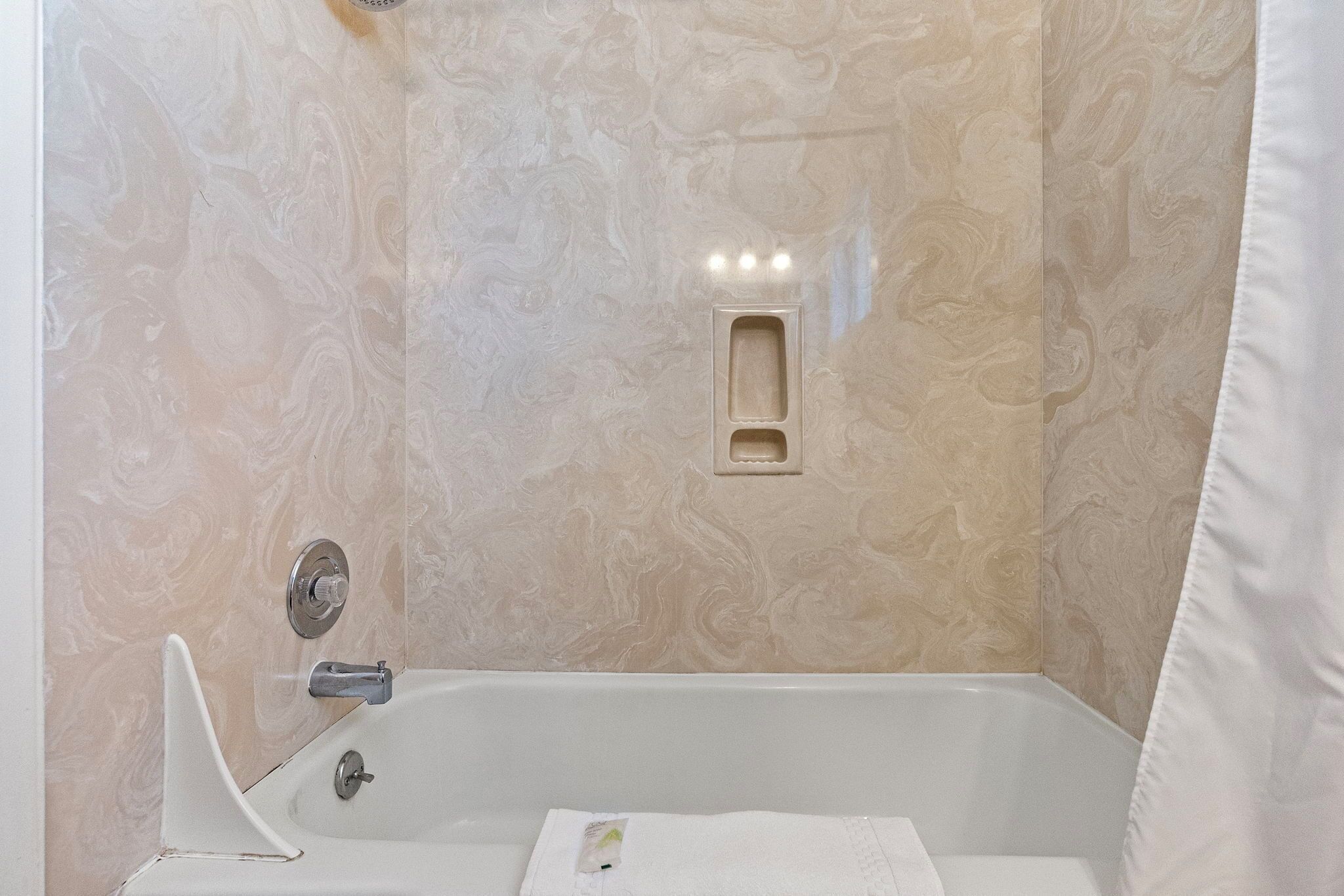 Une salle de bain avec un mur en marbre, une baignoire et un espace douche.