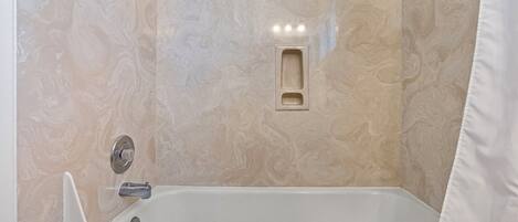 Une salle de bain avec un mur en marbre, une baignoire et un espace douche.
