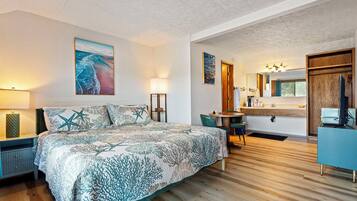 A bedroom with a large bed, a desk, and a bathroom.