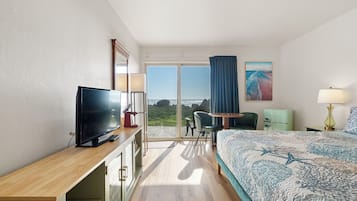 Een hotelkamer met een groot bed, een bureau met een televisie, een stoel, een klein tafeltje en uitzicht op de omgeving.