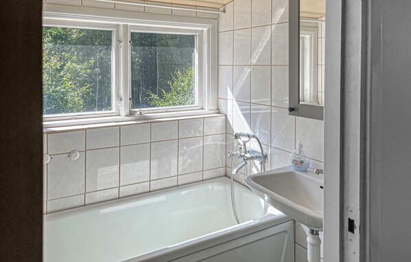 Un baño con bañera, lavamanos y ventana.