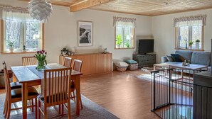 Un salon chaleureux avec un plafond en bois, un coin repas avec une table et des chaises, et un canapé.