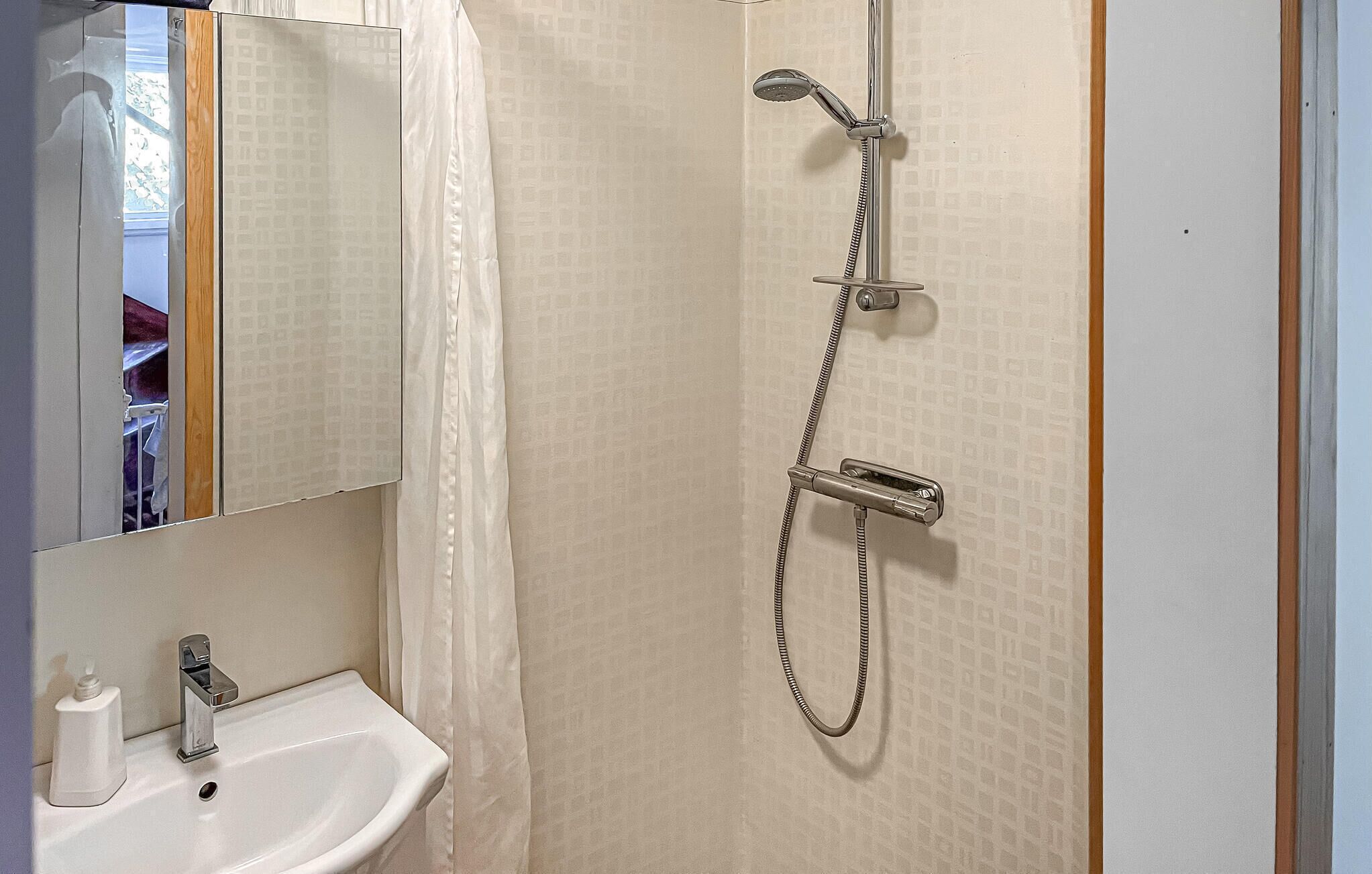 A bathroom with a shower, sink, and mirror.