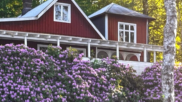 Une maison rouge avec un porche blanc et une fenêtre.