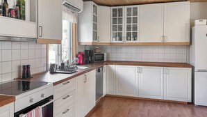 Une cuisine avec des meubles blancs, un plan de travail en bois, un four à micro-ondes et un lave-vaisselle.