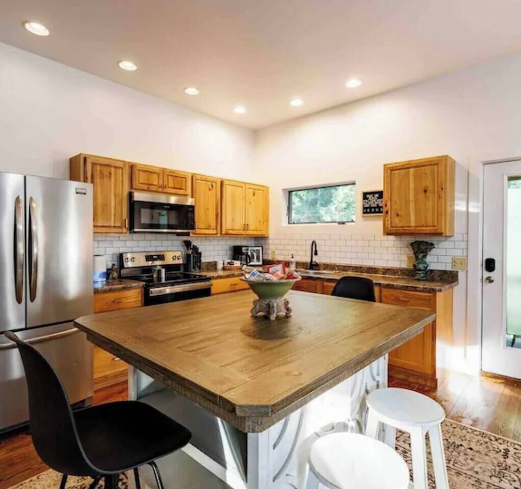 A modern kitchen with wooden cabinets, stainless steel appliances, and a central island with stools.