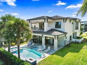 A two-story house with a swimming pool, covered patio, and a well-maintained lawn. - Luxe Palms at Bears Den-TB032 (Kissimmee)