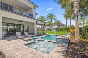 A modern two-story house with a swimming pool, outdoor seating, and palm trees.