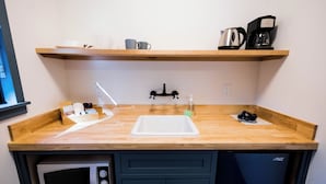 A compact kitchenette with a microwave, sink, and coffee maker.
