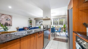 Une cuisine moderne dotée d’un îlot central, d’appareils électroménagers intégrés et d’un coin repas avec des chaises bleues.