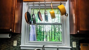 A kitchen with hanging pots and pans, a window with a view of trees, and a faucet. - Adults Only - Cozy, Kinky Hideaway Perfect for Couples (Atlanta)