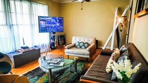 A living room with a television, sofa, armchair, coffee table, and a decorative vase. - Adults Only - Cozy, Kinky Hideaway Perfect for Couples (Atlanta)