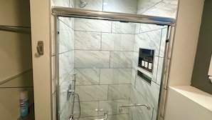 Eine moderne Dusche mit Glastür, Duschbrausehandstück und Zusatzbrause.
