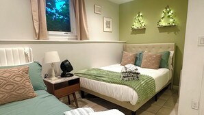 Ein Schlafzimmer mit zwei Betten, einem Nachttisch mit Lampe, einem Heizkörper und einem Fenster mit Vorhängen.