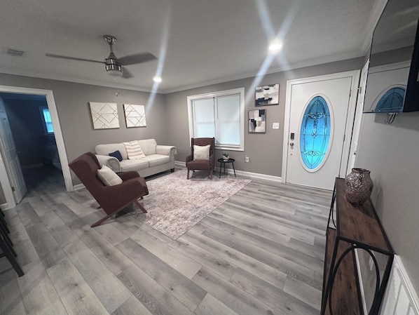A spacious living room with a ceiling fan, a sofa, a chair, and a rug.