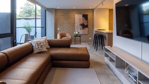A modern living room with a sectional sofa, a dining area, and a TV wall. - Elegant 3 bedroom apartment in quiet and central area 201 (Medellín)