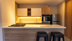 A modern kitchen with a central island, two bar stools, wooden cabinets, and built-in appliances. - Elegant 3 bedroom apartment in quiet and central area 201 (Medellín)