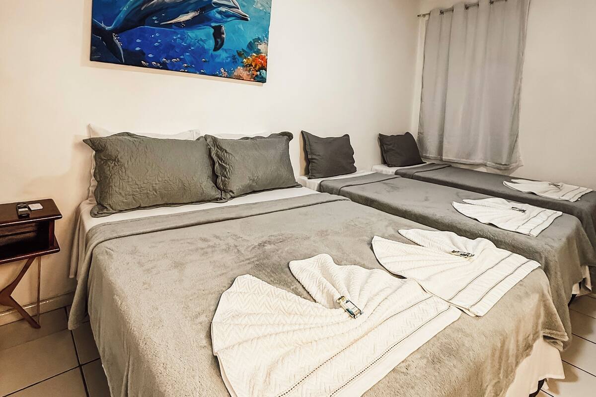 Ein Hotelzimmer mit zwei Betten, einem Bild von einem Delfin und einem Fenster mit Vorhängen.