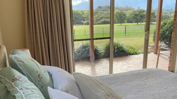 A bedroom with a large window offering a view of a green field and trees. - Vista 2 drop the bags and look at the view (Yarra Junction)
