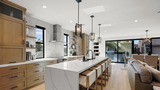 A modern kitchen with a large island, wooden cabinets, and pendant lighting. - Brand New w/ Luxury Amenities | AC | Fire Pit | Walk to Beach, Bay, Shops, Eateries (San Diego)