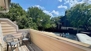 Eine Holzterrasse mit zwei Stühlen und Blick auf einen Poolbereich.