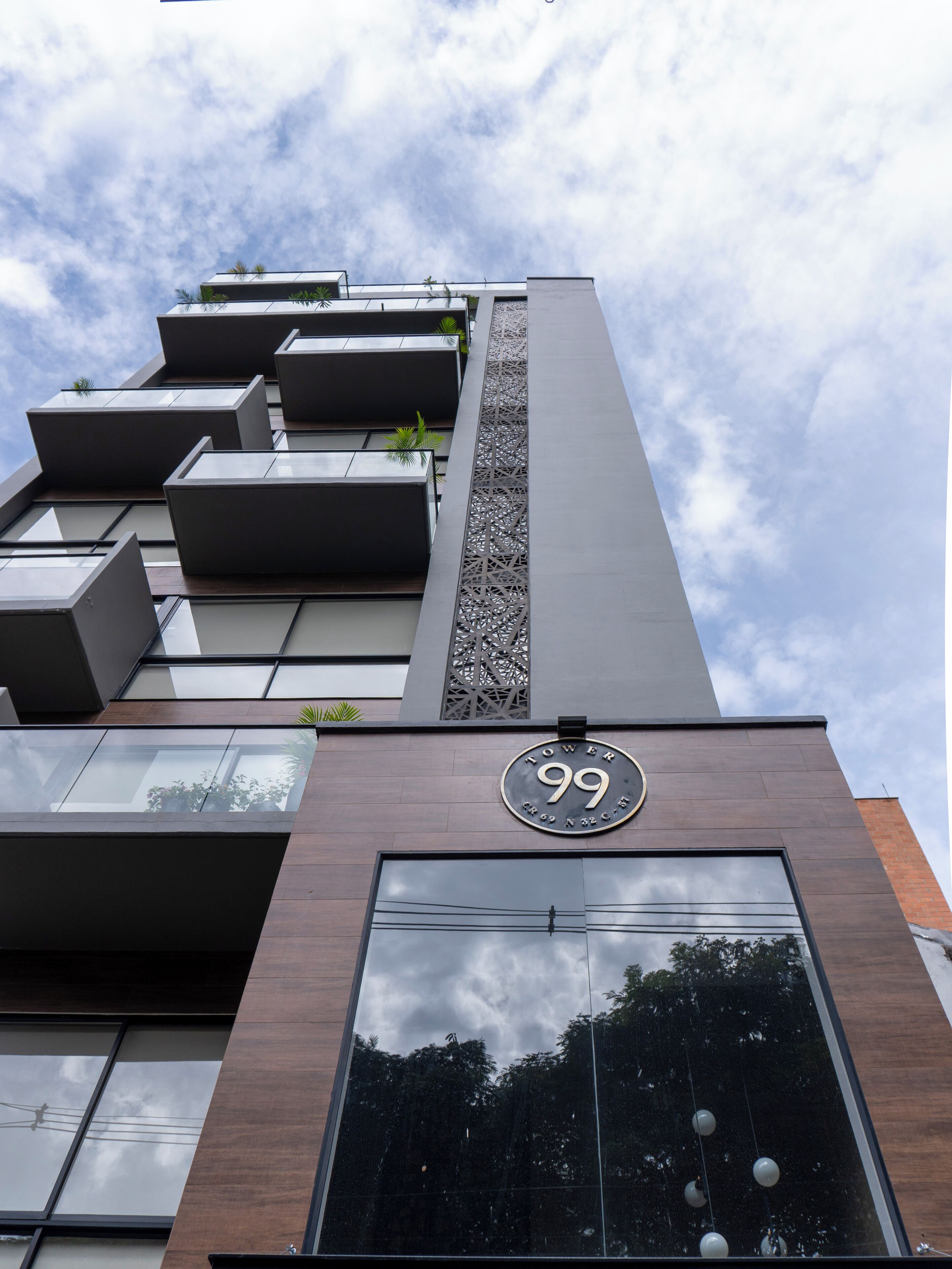 A modern building with a prominent '99' sign, large windows, and balconies with plants.