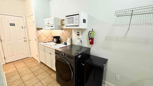 Une cuisine compacte équipée d’un lave-linge, d’un four à micro-ondes et d’une machine à café.