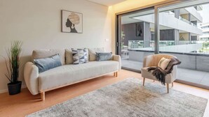 A modern living room with a sofa, armchair, and a large window.
