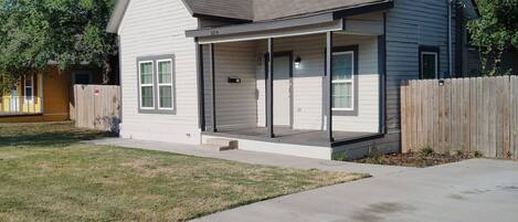 A single-story house with a front porch, a garage, and a fenced yard.