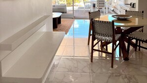A modern living room with a dining area, large windows, and a view of the outdoors. - Sea Breeze - NBBC - 2 bedrooms beachfront (Marigot)