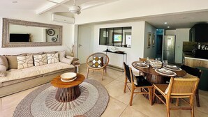 A modern living room with a sofa, coffee table, and dining area with chairs and a table set for four.
