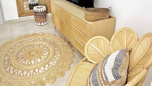 A living room with a television, wicker furniture, and a woven rug.