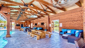 A covered outdoor area with wooden benches, a pool, and a seating area with cushions.