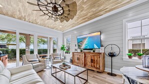 A spacious living room with a large TV, wooden cabinets, and a ceiling fan.