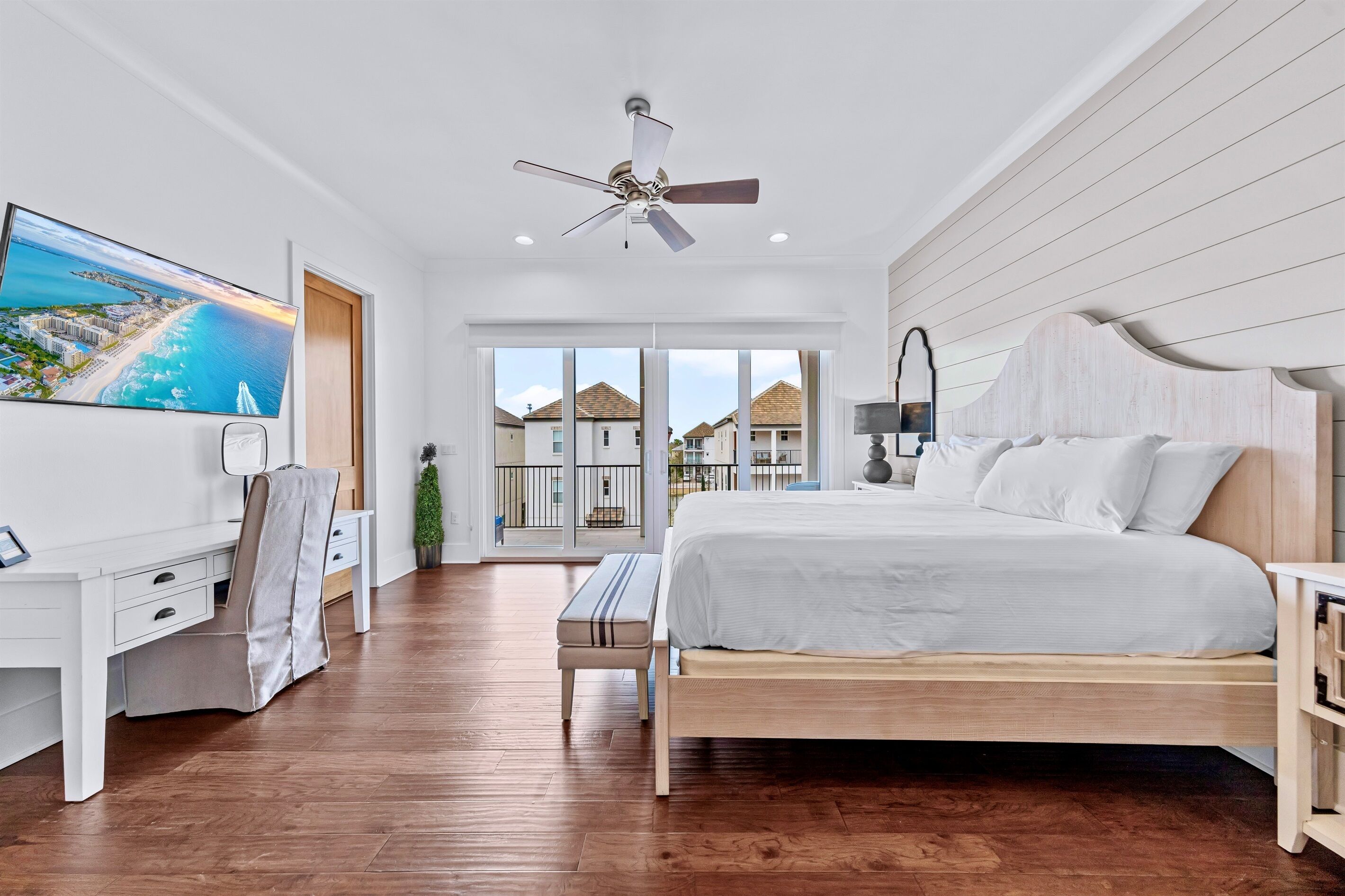 A modern bedroom with a large bed, a desk, and a television displaying a scenic view.