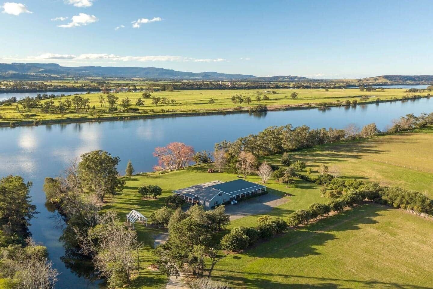 A large, open property with a lake, a covered outdoor area, and a well-maintained lawn.