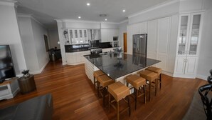 Una cucina moderna con mobili bianchi, un'isola centrale con sgabelli da bar e un frigorifero in acciaio inossidabile.