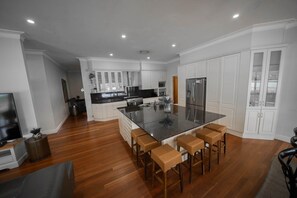 Una cocina moderna con armarios blancos, una isla central con taburetes y un refrigerador de acero inoxidable.