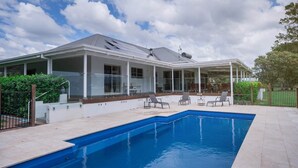 Una casa moderna con piscina, patio coperto e giardino recintato.