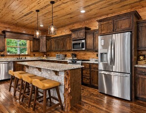 A modern kitchen with wooden cabinets, stainless steel appliances, and a large island with bar stools.